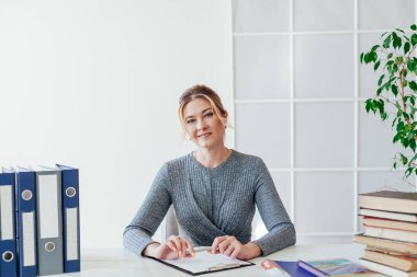 Ofiste kitapları olan güzel bir iş kadını portresi.