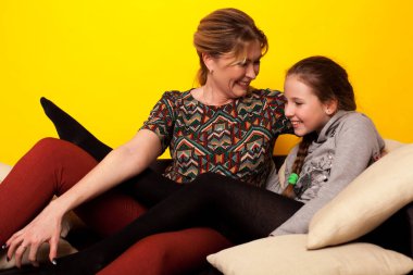 Güzel bir kız ve Wjman siyah bir kanepede uzanır. Yastıklı ev yapımı giysiler içinde.