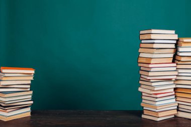 Üniversite sınavları için kütüphanenin yeşil arka planı üzerine bir sürü eğitici kitap