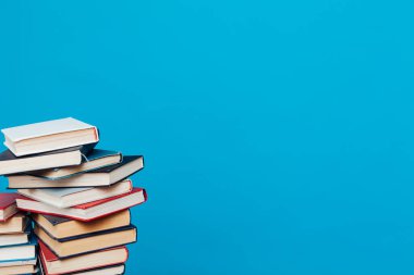 Kütüphanenin mavi arka planında üniversite sınavları için bir sürü eğitici kitap var.
