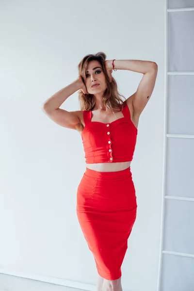 Portrait d'une belle femme blonde à la mode dans une robe rouge dans une pièce blanche — Photo