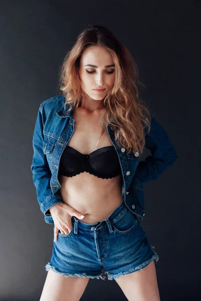 Portrait of a beautiful fashionable woman in black lingerie and denim shorts — Stock Photo, Image
