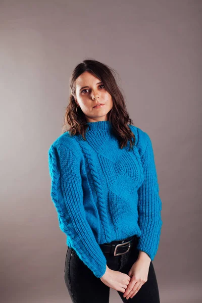 Портрет тощей модной брюнетки в джинсах и голубом свитере — стоковое фото