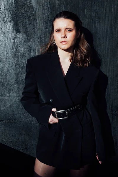 一个穿着黑色夹克的漂亮时髦女人面对着黑墙的画像 — 图库照片