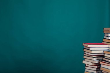 Üniversite kütüphanesindeki sınavlar için yeşil bir arkaplan üzerine bir yığın eğitim kitabı