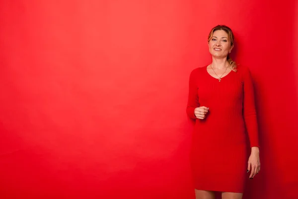 Žena čtyřicet let v šatech na červeném pozadí — Stock fotografie
