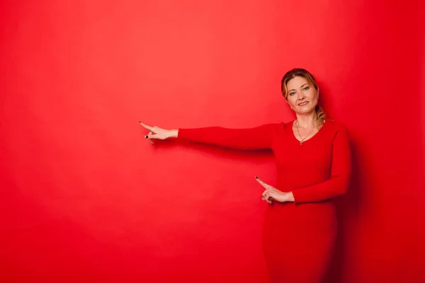 Žena čtyřicet let v šatech na červeném pozadí — Stock fotografie