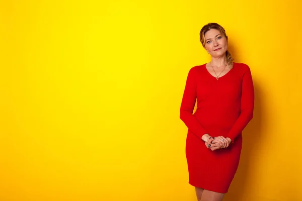 黄色の背景をしたドレスを着た40歳の女性 — ストック写真