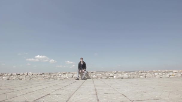 Homme Assis Sur Bord Ciel Bleu Arrière Plan — Video