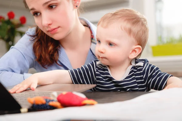 Joven madre trabajando con su bebé — Foto de Stock