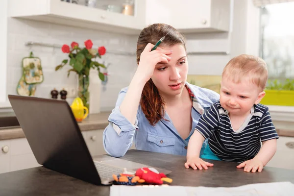 Jeune mère travaillant avec son bébé — Photo