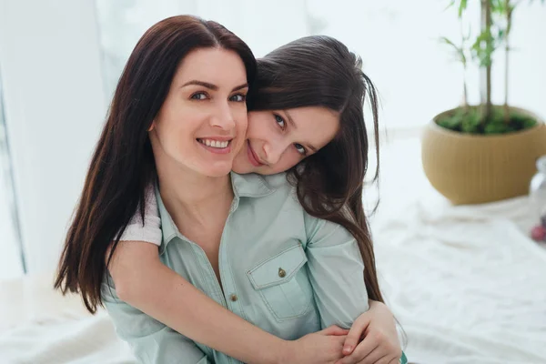 Hermosa madre y su linda hija sonriendo y posando en casa . — Foto de Stock