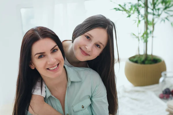 Mooie moeder en haar schattige dochter glimlachend en poseren thuis. — Stockfoto