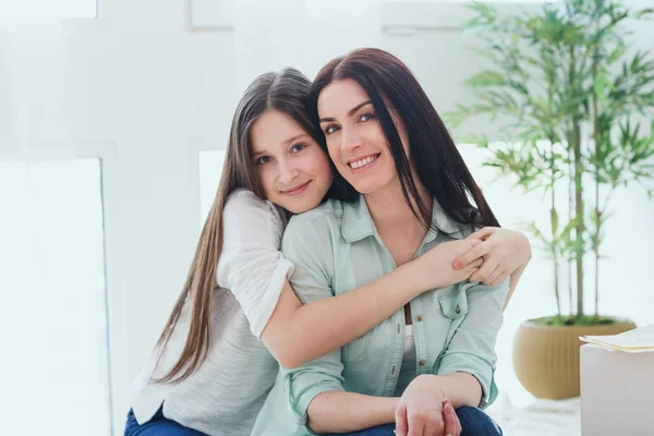 Hermosa madre y su linda hija sonriendo y posando en casa . — Foto de Stock