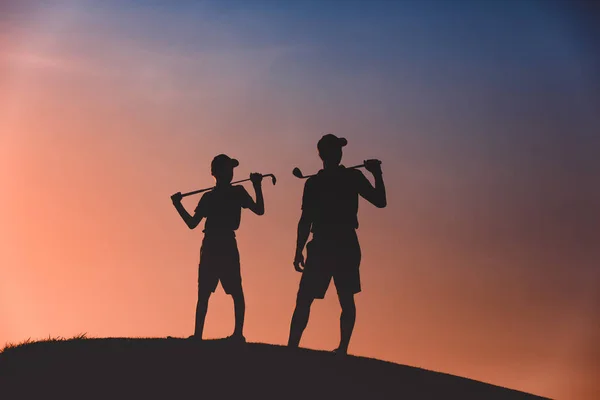 Hombre con su hijo golfistas silueta — Foto de Stock
