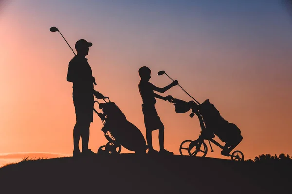 Hombre con su hijo golfistas silueta — Foto de Stock