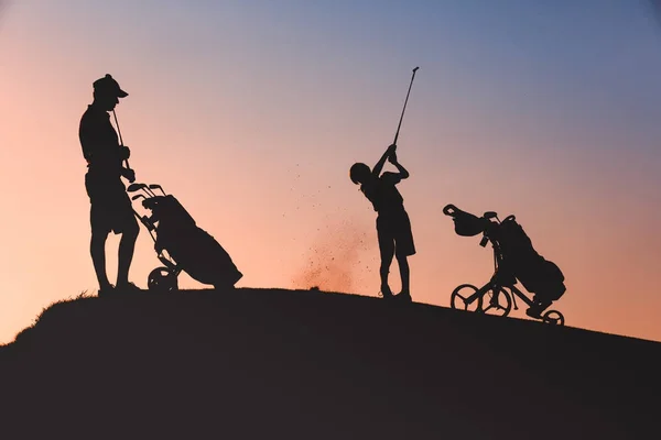 Hombre con su hijo golfistas silueta — Foto de Stock