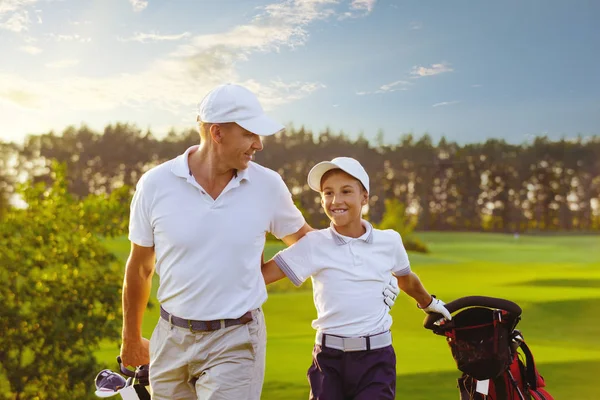 Hombre con su hijo golfistas caminando en el campo de golf — Foto de Stock