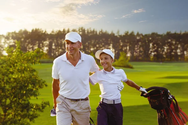 Hombre con su hijo golfistas caminando en el campo de golf — Foto de Stock