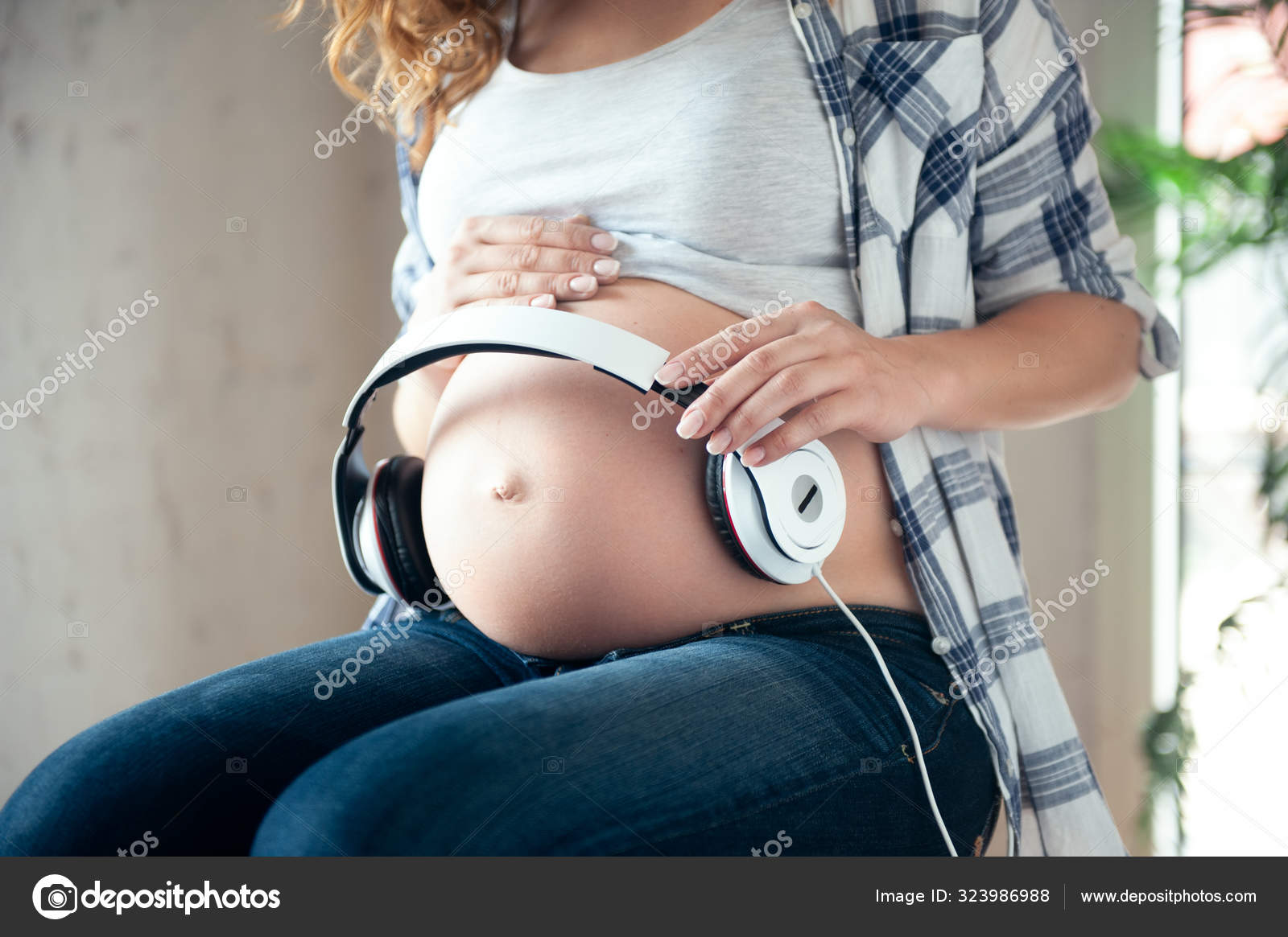 Pregnant woman holding headphones on her belly. Stock Photo by  ©stock.sokolov.com.ua 323986988