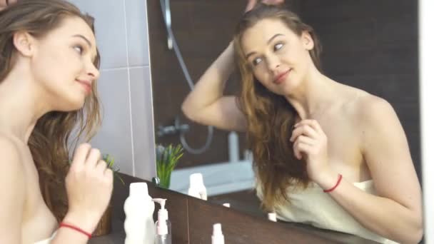 Beautiful young woman looking in mirror at bathroom 4k footage — Stock Video