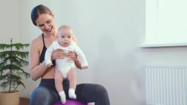 Mom does fitness with the baby at home — ストック動画