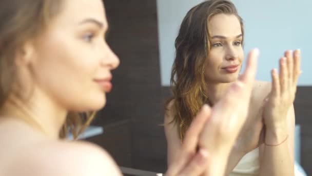 Hermosa joven mujer mirando en el espejo en el cuarto de baño 4k metraje — Vídeos de Stock