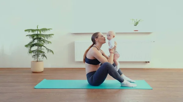 Mamá hace fitness con el bebé en casa — Foto de Stock