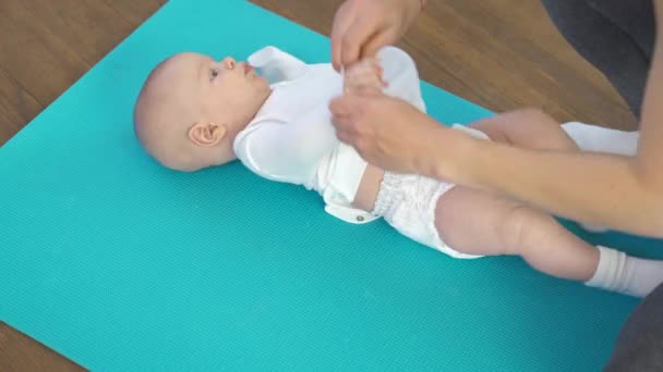 Maman habille un enfant sur un tapis de fitness — Video