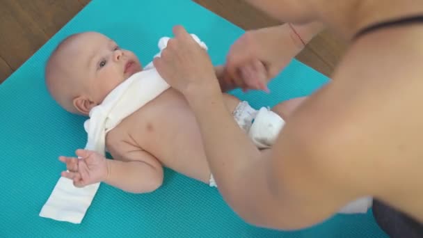 Maman habille un enfant sur un tapis de fitness — Video
