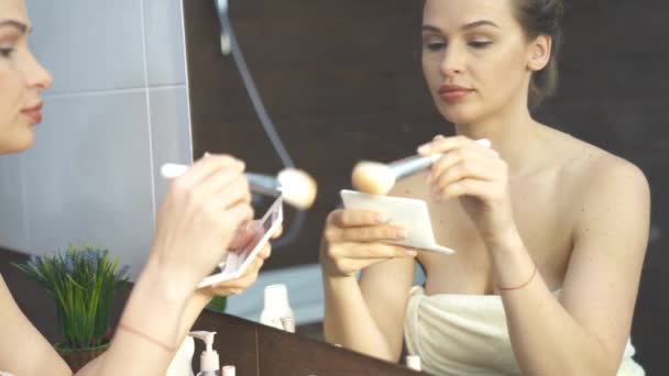 Красива жінка робить макіяж перед дзеркалом у ванній — стокове відео