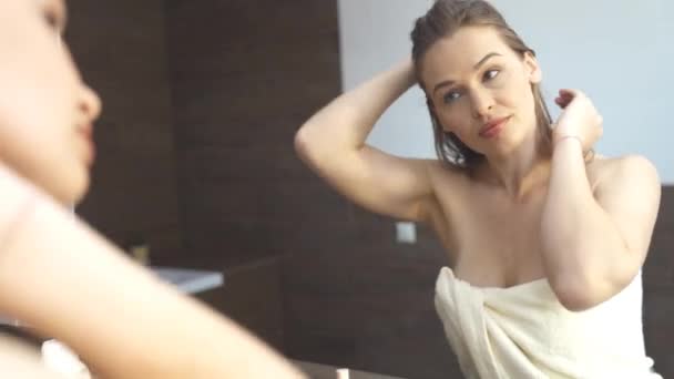 Beautiful young woman looking in mirror at bathroom 4k footage — Stock Video
