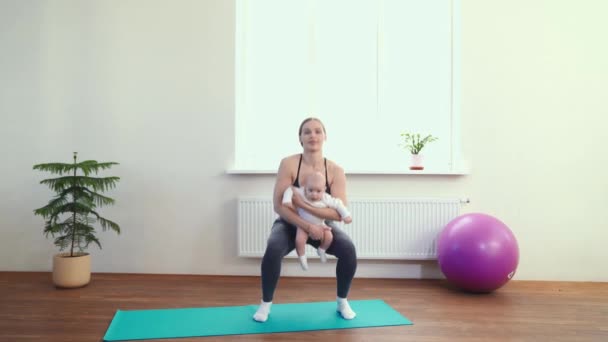 Mãe faz fitness com o bebê para os músculos nos braços e pernas . — Vídeo de Stock