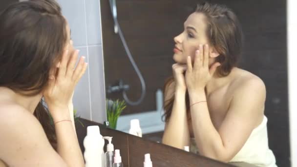 Hermosa joven mujer mirando en el espejo en el cuarto de baño 4k metraje — Vídeos de Stock