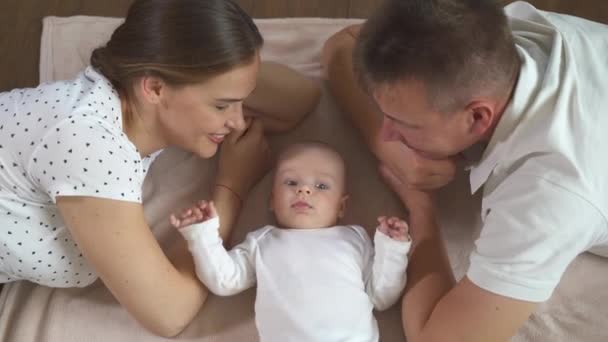 Улыбающаяся семья в постели, где крутой план лица папа, мама и маленький сын . — стоковое видео