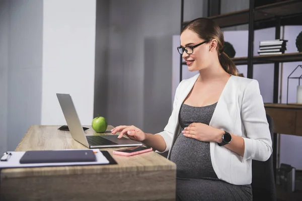 Mujer embarazada joven de negocios utilizando un ordenador portátil en la oficina — Foto de Stock