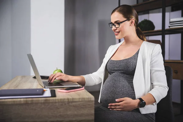 Mujer embarazada joven de negocios utilizando un ordenador portátil en la oficina — Foto de Stock