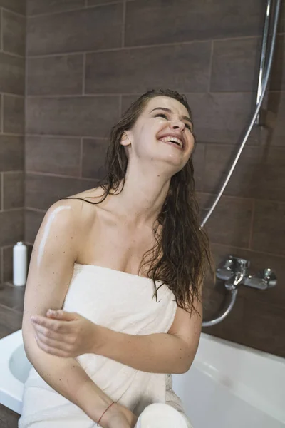 Woman applying cream to skin while body in bathroom. — Stock Photo, Image