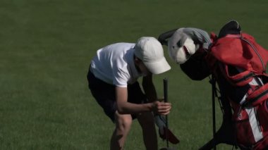 Mutlu çocuk golfçü. Gün batımında golf sahasında neşeli genç çocuk
