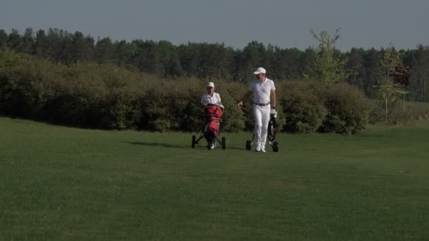 Gelukkig man met zijn zoon golfers wandelen op perfecte golfbaan op zomerdag — Stockvideo