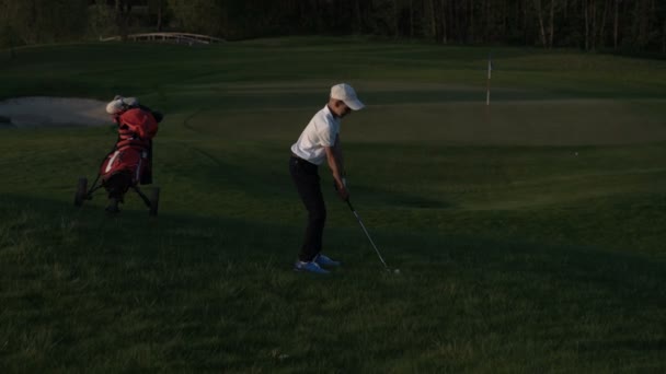 Happy boy golfer. Cheerful junior boy on the golf course at sunset — Stock Video