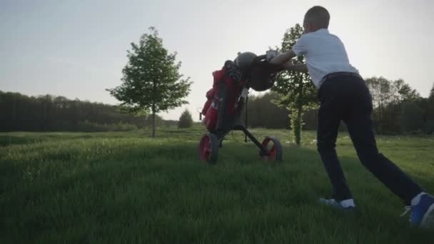 幸せな少年ゴルファー。夕暮れ時のゴルフコースで陽気な少年男子 — ストック動画