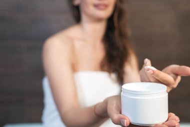 güzel bir genç kadın vücut losyonu uygulanıyor.