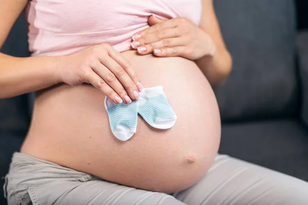 Belly av gravid kvinna med baby strumpor — Stockfoto