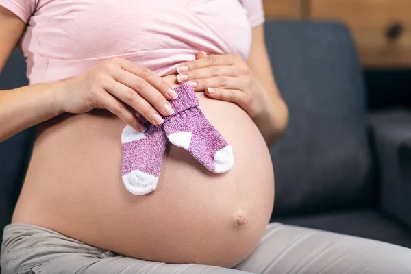 赤ちゃんの靴下を持つ妊婦の腹 — ストック写真