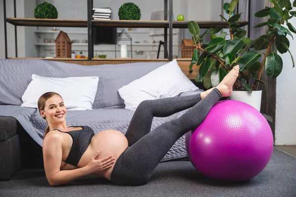 Mujer embarazada está haciendo ejercicios con pelota de gimnasia — Foto de Stock