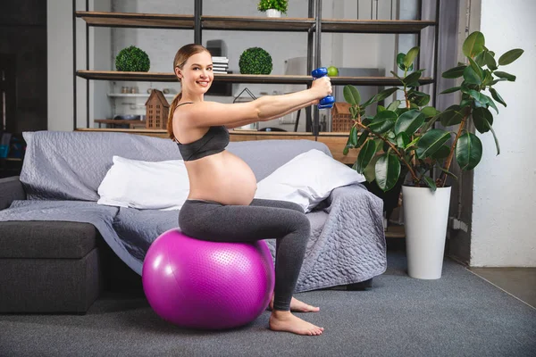 Mujer embarazada está haciendo ejercicios con pelota de gimnasia. rodaje en un estudio fotográfico — Foto de Stock