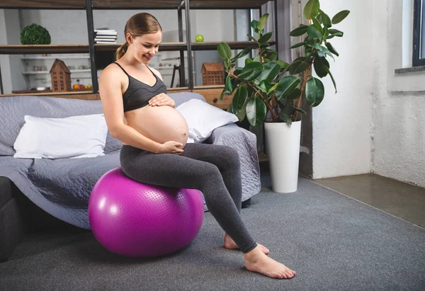 Gravid kvinna utövar hemma med fitness boll. fotografering i en fotostudio Stockbild