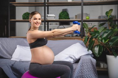 Hamile kadın jimnastik topuyla egzersiz yapıyor.