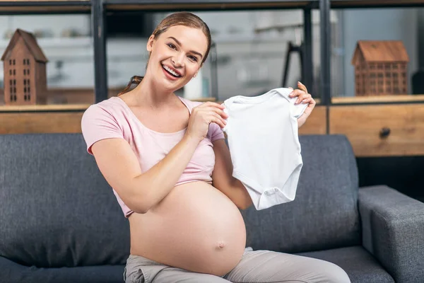 Hälsosam och glad mor att vara förbereder en nyfödd skjorta för baby. — Stockfoto